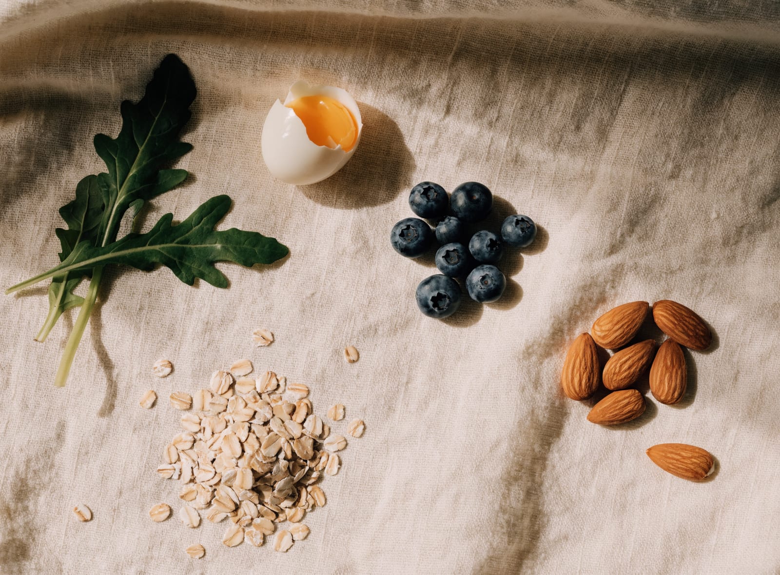 Arugula, a cracked soft-boiled egg, blueberries, oats, and almonds on linen